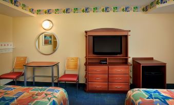 a room with a large wooden cabinet , a television on top of the cabinet , and two chairs at Disney's All-Star Sports Resort