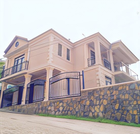 a two - story house with a stone wall and black gate is situated on a dirt road at Castle