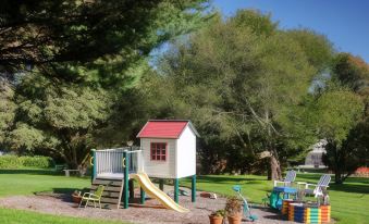 a small wooden house with a red roof , surrounded by trees and greenery , in a park - like setting at Yarra Gables