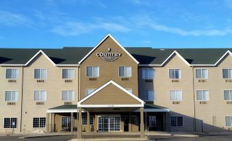 "a large , beige - colored hotel with the name "" country inn & suites "" on it , under a clear blue sky" at Country Inn & Suites by Radisson, Watertown, SD