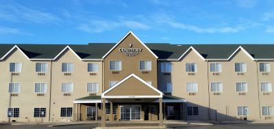 "a large , beige - colored hotel with the name "" country inn & suites "" on it , under a clear blue sky" at Country Inn & Suites by Radisson, Watertown, SD