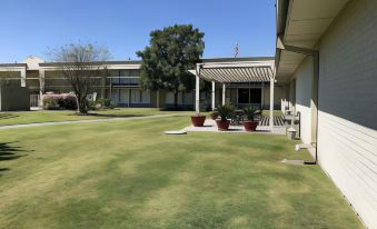 a grassy area with a building and trees in the background , under a clear blue sky at Ramada by Wyndham New Iberia