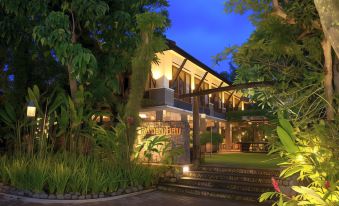 a large house with a restaurant sign on the front , surrounded by lush greenery and trees at Rumah Batu Boutique Hotel