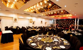 a well - decorated banquet hall with round tables set for a formal event , all set for a dinner service at Mercure Maitland Monte Pio