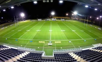 a large , well - lit sports stadium with rows of empty seats and bleachers in the foreground at Direct Collective - Breeze on Brightwater