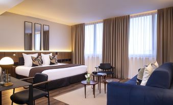 a large bed with a brown and white comforter is in the center of a room with chairs , couches , and windows at Hotel du Port