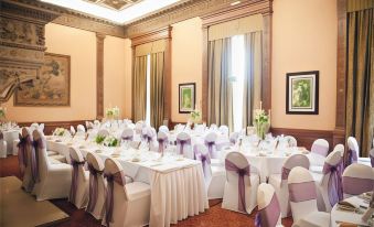 a well - decorated banquet hall with tables covered in white tablecloths and chairs arranged for a formal event at Macdonald Elmers Court Hotel