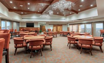 a large room with multiple tables and chairs , chandeliers , and a view of another building at Norfolk Lodge & Suites, Ascend Hotel Collection