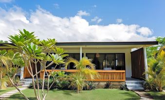a house with a wooden deck and tropical plants is surrounded by greenery and blue skies at Turtle Bay Lodge