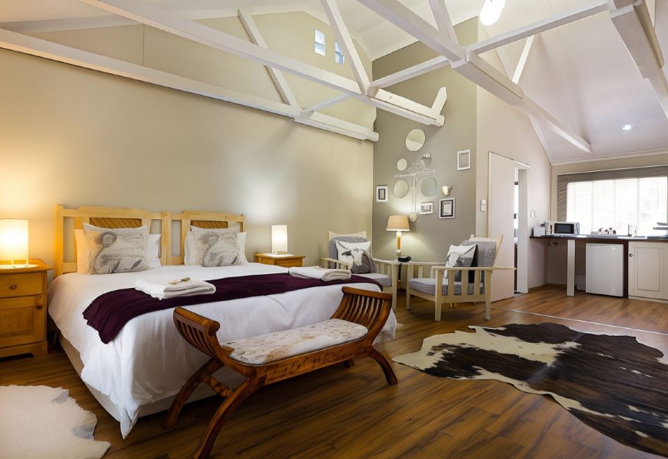 a cozy bedroom with a white bed , wooden furniture , and a cowhide rug on the floor at Morning Glory Cottages