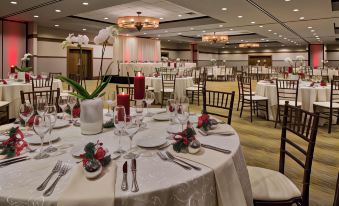 a large dining room with several tables set for a formal event , each decorated with white and red flowers at DoubleTree by Hilton Hotel Libertyville - Mundelein
