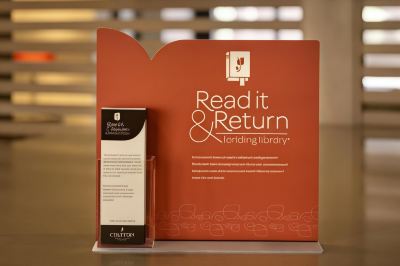 "a red display sign for the "" read it and return lending library "" campaign , with a close - up of a "" cedrick library """ at Country Inn & Suites by Radisson, Watertown, SD