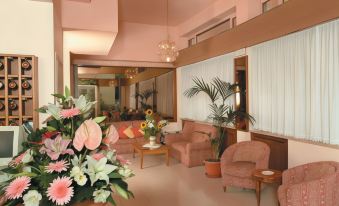 a living room with pink walls and furniture , including couches and chairs , arranged around a large flower arrangement at PRIMAVERA