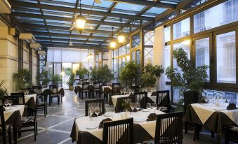 a large , modern restaurant with multiple dining tables and chairs arranged for a group of people at Majestic Hotel