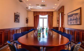 a conference room with a wooden table surrounded by blue chairs , and several bottles of alcohol on the table at Hotel Savoy