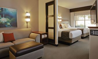 a modern hotel room with a bed , couch , and desk , along with two wall sconces at Hyatt Place Saratoga Malta