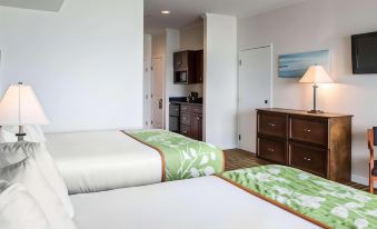 a hotel room with two beds , a nightstand , and a kitchenette , all decorated in white and green colors at Island Inn & Suites, Ascend Hotel Collection