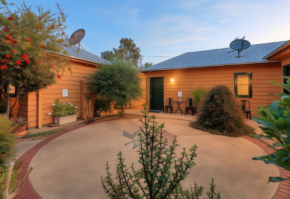 a wooden house with a satellite dish on the roof is surrounded by trees and plants at Prince of Wales Hotel Gulgong