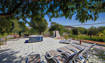 a rooftop patio with lounge chairs and a hot tub , surrounded by trees and a brick wall at Villa Rustica Dalmatia