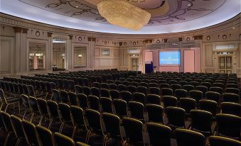 a large , empty conference room with rows of chairs and a screen at the front at Midland Hotel, Bradford