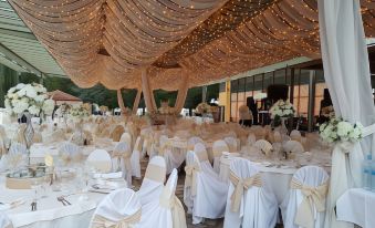 a large dining room with multiple tables covered in white tablecloths and adorned with elegant white and gold decorations at Hotel Bellevue