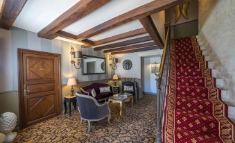 a cozy living room with wooden beams on the ceiling , a couch , and a chair at Hotel Saint-Martin - Younan Collection