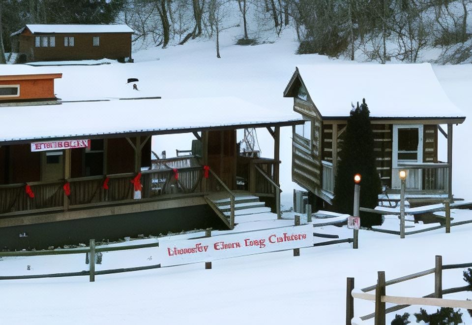 a snow - covered cabin surrounded by trees , with a sign indicating that it is a cabin resort at Linville River Log Cabins