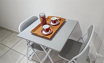 a dining table with two cups and a tray placed on top of it , along with a laptop nearby at Vichy