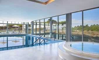 a modern indoor pool area with a circular hot tub , surrounded by large windows and greenery at The Bear, Cowbridge