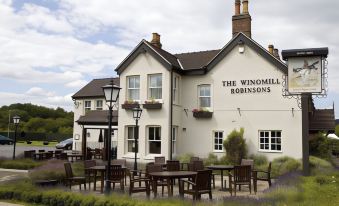 "a large white building with the name "" the winomen robinsons "" on it , surrounded by a well - maintained garden with potted plants" at The Windmill Inn