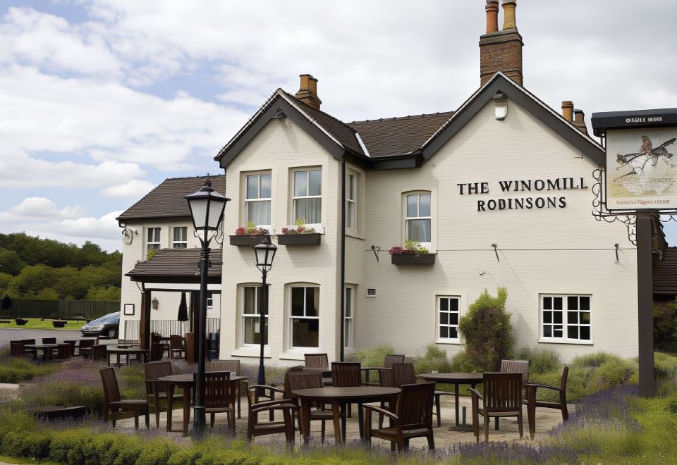 "a large white building with the name "" the winomen robinsons "" on it , surrounded by a well - maintained garden with potted plants" at The Windmill Inn