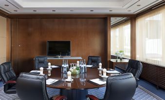 a conference room with a round table , chairs , and a tv mounted on the wall at Steigenberger Graf Zeppelin