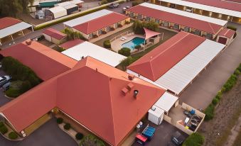 a large building with a red roof and multiple cars parked in the driveway surrounding it at Emerald Explorers Inn