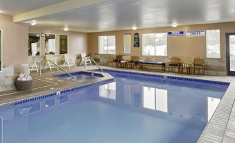 an indoor swimming pool with a blue interior , surrounded by chairs and tables for guests to enjoy at Yellowstone Park Hotel