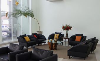 a spacious living room with black leather furniture , including chairs and a couch , arranged around a coffee table at Hotel Capital