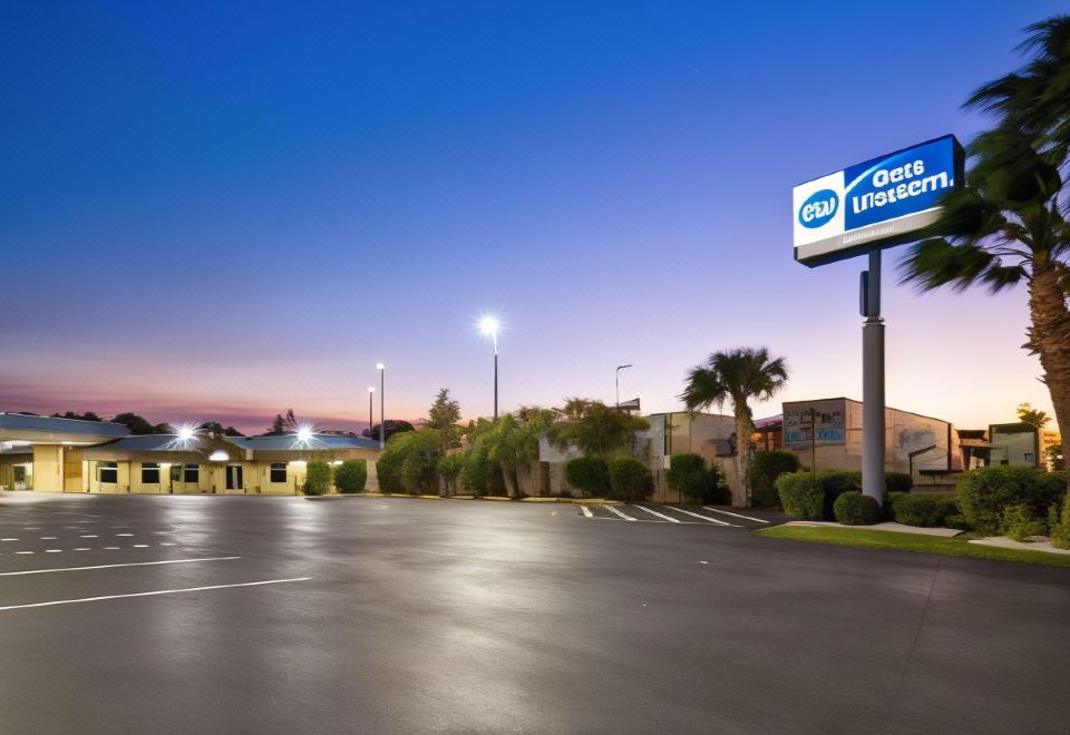 "a large parking lot with a "" best western "" sign in front of a building at dusk" at Ramada by Wyndham Cocoa