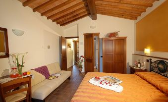 a cozy bedroom with wooden beams on the ceiling , a bed , and a couch , all decorated in a modern style at Antico Borgo Il Cardino