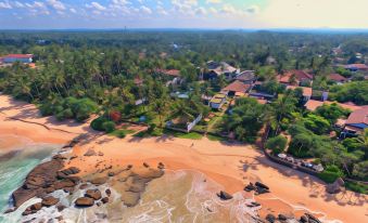 aerial view of a tropical beach resort with palm trees and a pool , surrounded by rocks and water at R Degrees