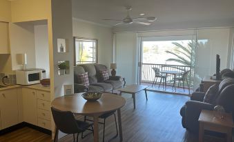 a living room with a couch , dining table , and chairs is shown next to a sliding glass door at Goldsborough Place Apartments