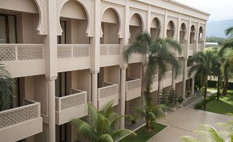 a building with multiple balconies and arches , surrounded by palm trees and greenery , in an urban setting at The Pade Hotel