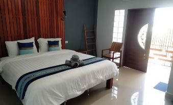 a large bed with white sheets and a blue blanket is in a room with wooden furniture at The Sekret Hotel