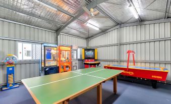 a large room with multiple arcade games , including a ping pong table , a pinball machine , and a air hockey table at Discovery Parks - Townsville