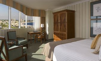 a hotel room with a bed , desk , chair , and window overlooking a cityscape , all furnished with wooden furniture at Hyatt Regency Long Beach