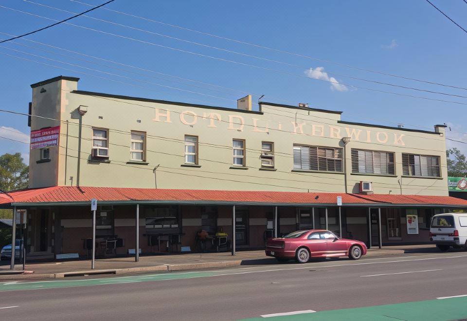 "a red car is driving down a city street in front of a hotel , with the word "" hotel "" written on the side of the building" at Hotel Kerwick