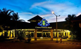 "a large hotel with a blue and gold sign that says "" crown victoria hotel "" in front of palm trees" at Crown Victoria Hotel Tulungagung