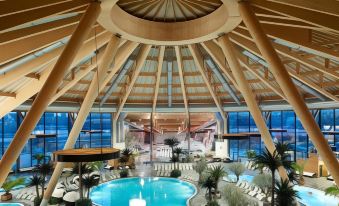 an indoor swimming pool surrounded by lounge chairs , with a large wooden ceiling above it at Courtyard Basel