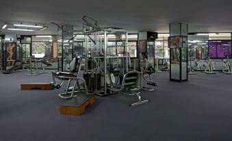 a well - equipped gym with various exercise equipment , including weight machines and benches , in a spacious room at Horison Ultima Bandung