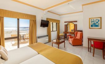 a spacious bedroom with a large bed , orange chair , and sliding glass door leading to an outdoor balcony at Hotel Casabela