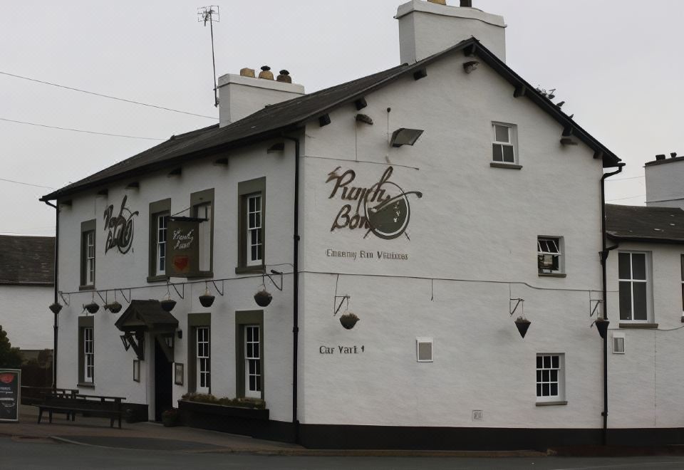 "a large white building with a black roof and windows , featuring the name "" five bells "" in black letters on the side" at The Punchbowl Hotel