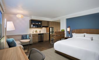 a modern hotel room with a large bed , wooden furniture , and a kitchenette area at Element Chelmsford